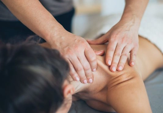 Zwei Hände, die den Nacken einer Frau massieren