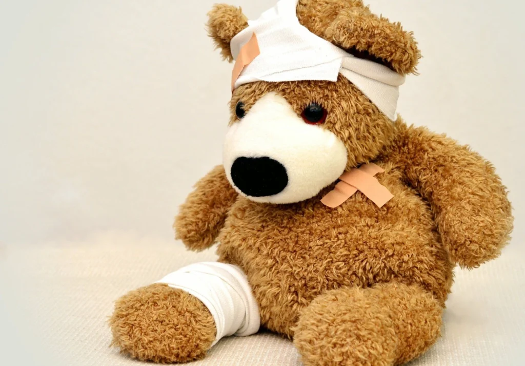 Ein Teddybär, der stellvertretend für Verletzungen mit Pflaster und Verband umhüllt ist